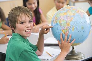 Student in class pointing at globe with students in background (selective focus)