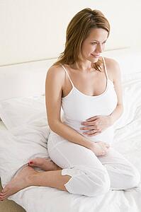 Pregnant woman sitting in bed smiling