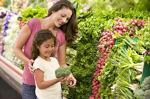 Mother and daughter shopping for broccoli at a grocery store