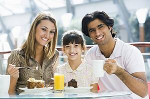 Family at restaurant eating dessert and smiling (selective focus)