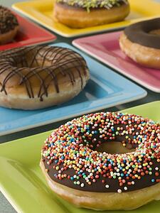 Selection Of Ring Doughnuts On A Different Coloured Plates
