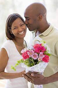 Husband and wife holding flowers and smiling