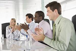 Four businesspeople in a boardroom applauding