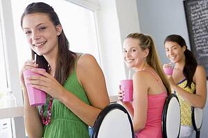 Three young women having a cold drink in a cafeteria