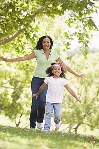 Woman and young girl running outdoors smiling