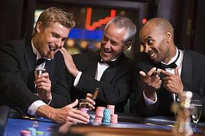 Three men in casino playing roulette and smiling (selective focus)