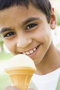 Young boy outdoors eating ice cream and smiling (selective focus)