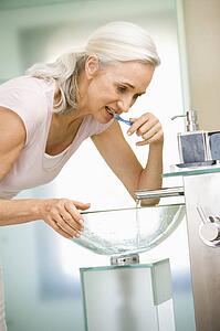 Woman in bathroom brushing teeth