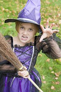 Young girl outdoors in witch costume on Halloween