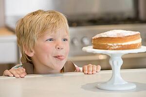 Young boy in kitchen looking at cake on counter