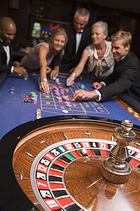 Group of people in casino playing roulette and smiling (selective focus)