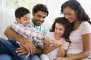Family in living room fighting over remote control smiling (high key)