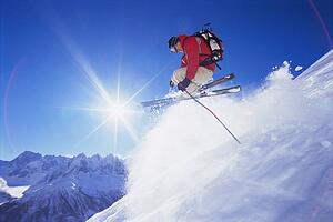 Skier jumping on snowy hill (lens flare)