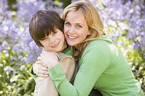 Mother and son outdoors embracing and smiling