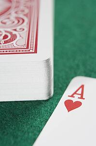 Deck of cards on a poker table with ace of hearts showing (close up/selective focus)