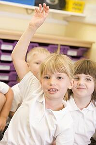 Student in class volunteering with students in background (selective focus)