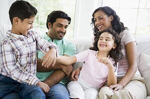Family in living room play fighting and smiling (high key/selective focus)