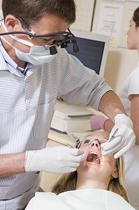 Dentist and assistant in exam room with woman in chair