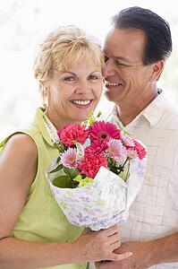 Husband and wife holding flowers and smiling