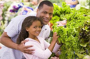 Father and daughter shopping for lettuce at a grocery store