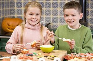 Brother and sister at Halloween making treats and smiling