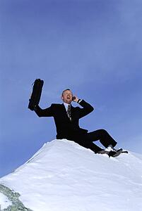 Businessman outdoors on snowy mountain using cellular phone and yelling