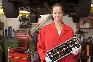 Mechanic holding car part smiling