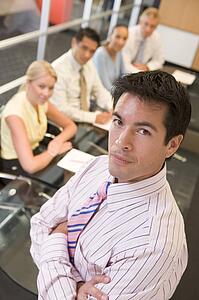 Businessman with four businesspeople at boardroom table in background