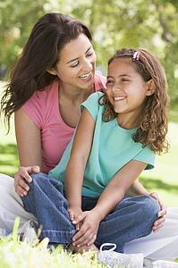 Woman and young girl sitting outdoors smiling