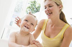 Mother giving baby bubble bath smiling