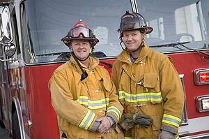 Two firemen standing in front of fire engine
