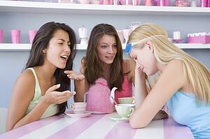 Young woman with a hangover sitting at a table with two friends