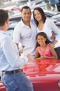 Mother and father with young daughter shopping for a new car