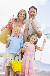 Family standing at beach with ice cream smiling