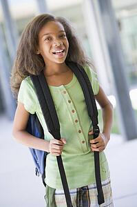 Student standing outside school smiling (selective focus)