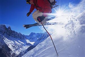 Skier jumping on snowy hill (lens flare)