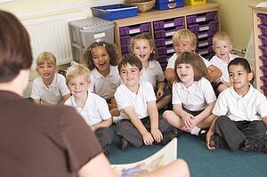 Students in class sitting on floor with teacher in foreground (selective focus)