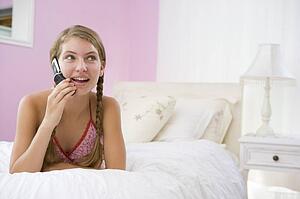 Teenage Girl Lying On Bed Using Mobile Phone 