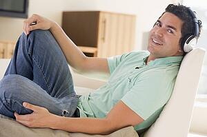 Man in living room listening to headphones smiling
