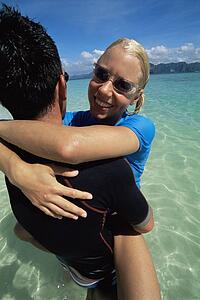 Couple outdoors embracing at beach and smiling