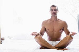 Man sitting on bed doing yoga