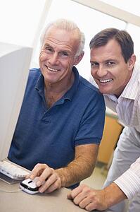 Two men at computer smiling (high key)