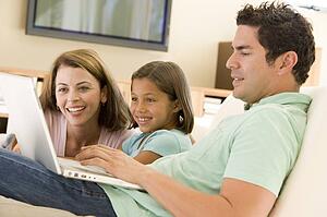 Family in living room with laptop smiling