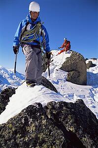 Two mountain climbers walking on snowy rocks (selective focus)