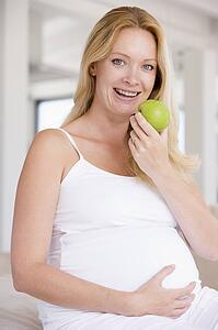 Pregnant woman eating apple and smiling