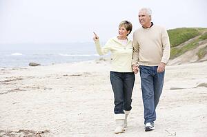 Couple holding hands at the beach smiling and pointing