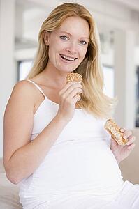 Pregnant woman eating bread and smiling
