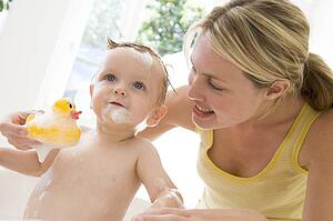 Mother giving baby bubble bath smiling
