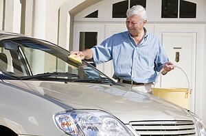 Senior man washing his car outside house