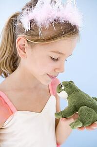 Young girl in princess costume kissing plush frog